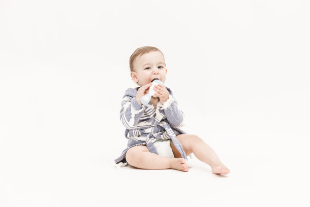 快乐的小男孩正坐着咬梳子图片下载