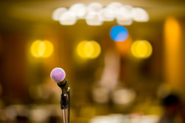 在音乐厅或会议室的麦克风柔和和模糊风格的背景。麦克风上方是会场或会议室背景的抽象模糊照片。图片下载