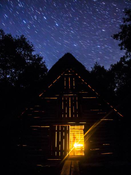 森林里的一间老木屋，里面点着星星下的蜡烛图片下载