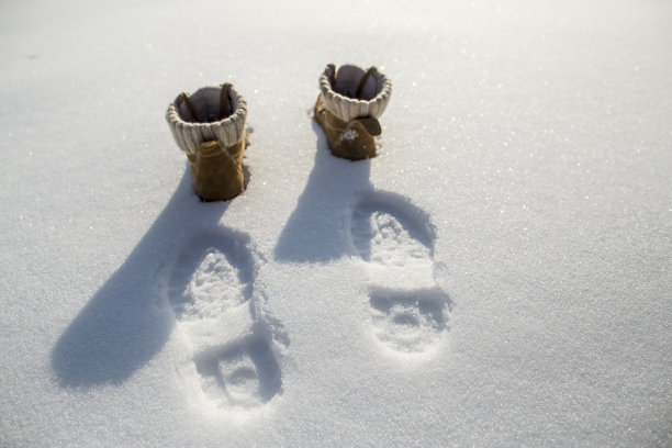 脚印和鞋子在纯洁的雪地上，霜冻的阳光里。图片下载