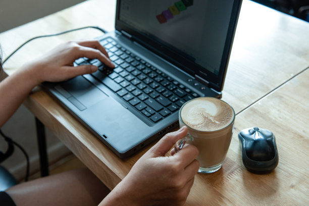 手拿拿铁咖啡的女人，她正在工作。图片下载