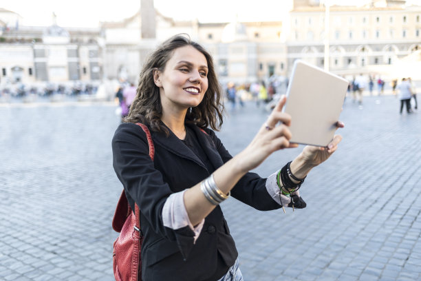 带着平板电脑在城镇广场微笑的视频博主图片下载