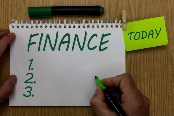 显示金融的文字标志。概念照片管理大型政府公司资金数额提供资金男人拿着马克笔笔记本晾衣夹提醒木制桌子杯子咖啡。图片下载