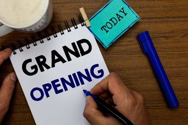 写的便条显示盛大开业。商业照片展示剪彩剪彩新业务首次正式推出日男子手拿马克笔笔记本衣夹提醒木桌咖啡。图片下载