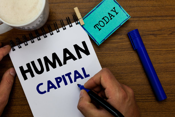 书写显示人力资本的便条。商业图片展示无形集体资源能力资本教育人拿着马克笔笔记本衣夹提醒木制桌子咖啡。图片下载