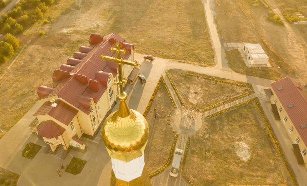 在日落时分，空中近距离观察令人惊叹的金色教堂建筑顶部的宗教交叉图片下载