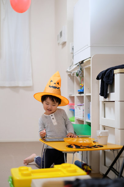 蹒跚学步的孩子与万圣节帽子看平板电脑图片下载