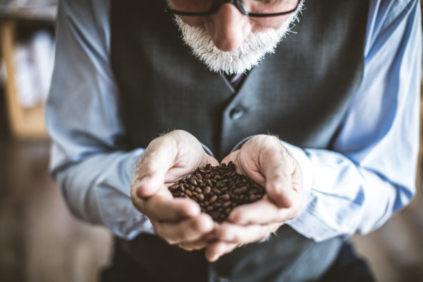 老人闻着他捧起的手里的咖啡粉图片下载