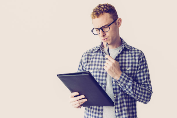 沉思的红发年轻人看着文件夹图片下载