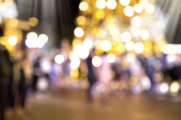 夜晚，模糊的圣诞装饰灯和城市广场上的人群图片下载