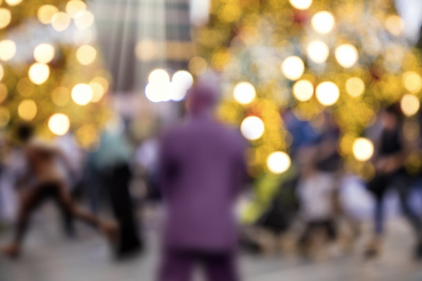 夜晚，模糊的圣诞装饰灯和城市广场上的人群图片下载