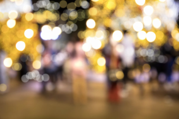 夜晚，模糊的圣诞装饰灯和城市广场上的人群图片下载