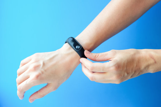 蓝色背景下的女人手拿健身追踪器素材图片