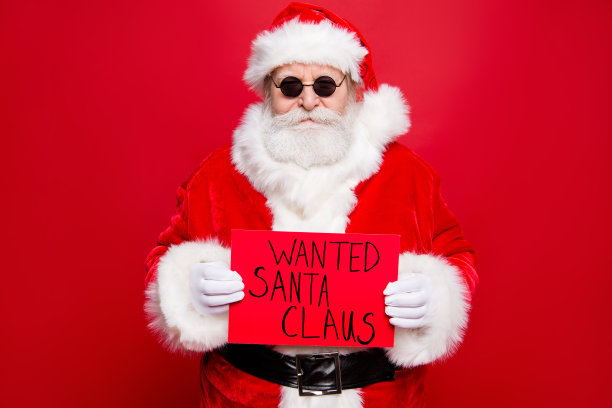 圣诞期间冬季活动概念。冷静自信的危险犯罪的爷爷，老圣诞老人戴着眼镜，戴着白胡子的手套，手里拿着一张被孤立在红色生动的背景上的照片图片下载