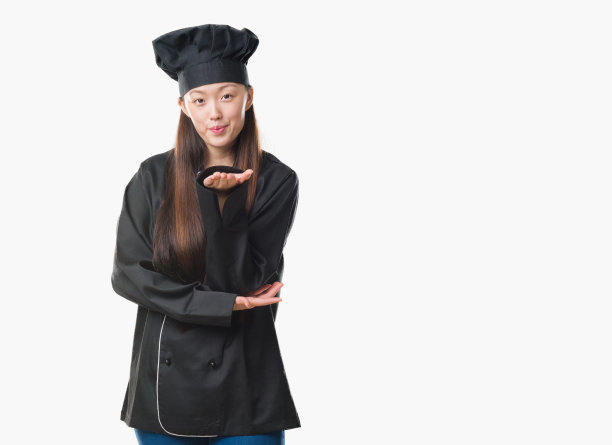 年轻的中国女子在孤立的背景下穿着厨师制服看着镜头，用手在空中飞吻是可爱和性感的。爱的表达。图片下载