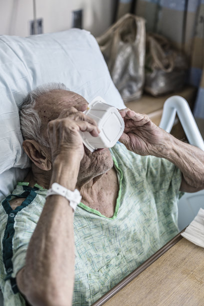 老年男子医疗病人在医院的床上喝最后一滴早餐麦片牛奶图片下载