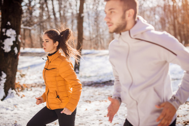 一对健身夫妇在雪山做冬季早操。图片下载
