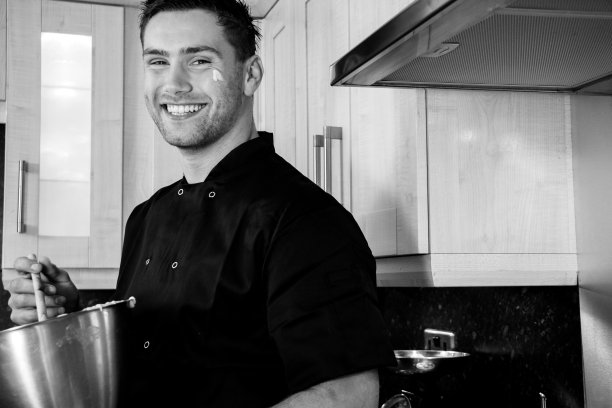 英俊的厨师微笑着站在厨房准备烘焙图片下载