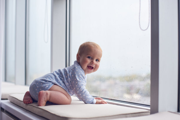 小男孩爬到大窗户附近图片下载