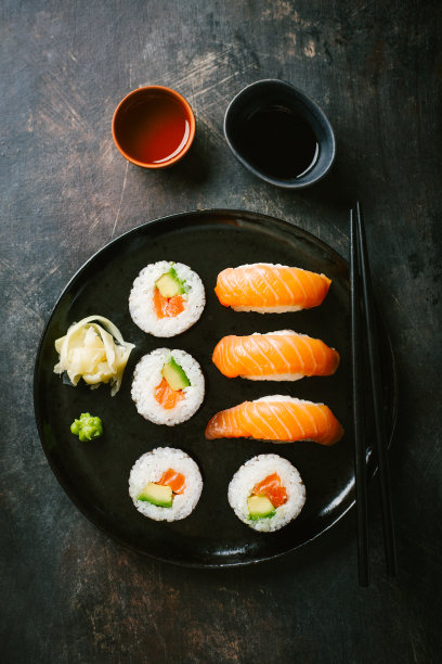 寿司装在黑色的盘子里，放在黑色的桌子上图片下载
