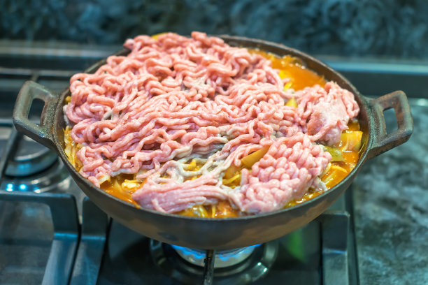 厨房里的煤气炉上的锅里放着肉末做的食物图片下载
