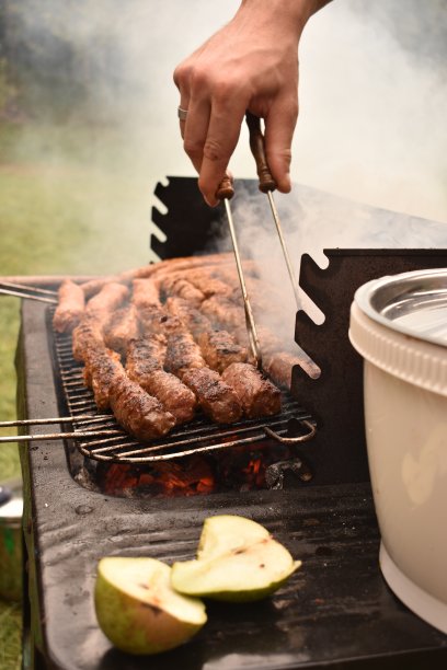 烹饪食物放在烧烤架上，用手夹准备。图片下载