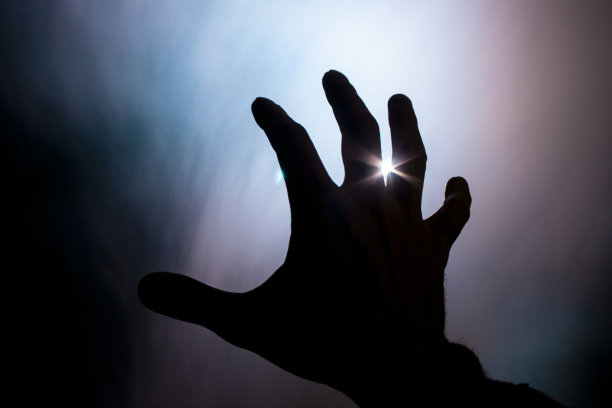 在刺眼的阳光下，模糊的手在火中的烟雾中图片下载