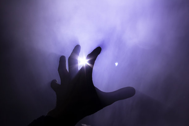 在刺眼的阳光下，模糊的手在火中的烟雾中图片下载