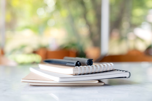 书和笔记本和笔在桌子上模糊的绿色自然背景素材图片