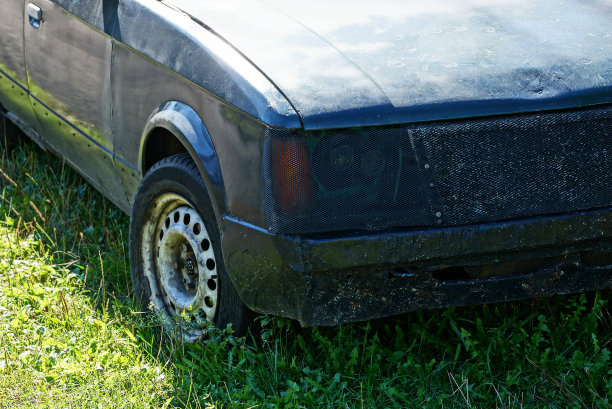 一辆黑色旧汽车的一部分，车轮保险杠和前灯在绿色草地上图片下载