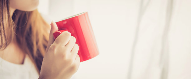 横幅网站美丽的年轻亚洲女子以喝咖啡杯站立窗帘窗背景在卧室，女孩在家里放松早晨，生活理念。图片下载