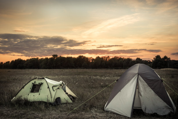 在夏季的平原和假日露营期间，露营地点的帐篷和日落的天空图片下载