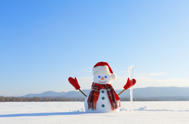 蓝眼睛微笑雪人戴着红帽子，手套和格子围巾拿着冰柱。快乐寒冷的冬日早晨。场雪。图片下载