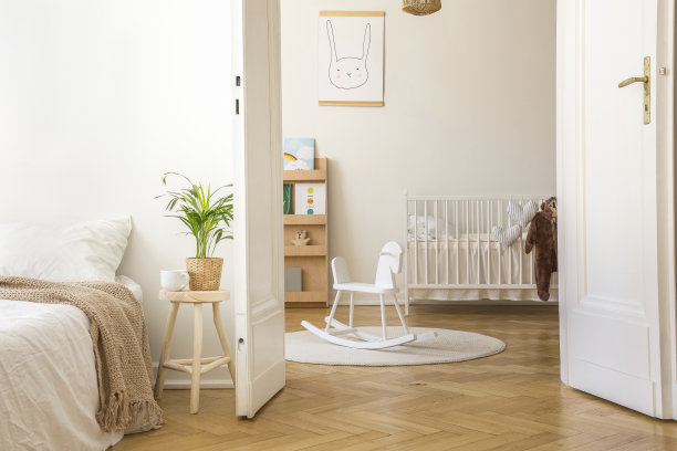 在白色卧室内的床旁边的凳子上，地毯和摇篮上有摇马。真实的照片图片下载