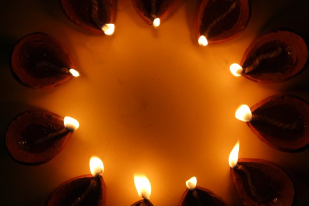 美丽的股票照片的传统橙色棕色赤陶土粘土diya灯燃烧在一个圆圈形成，黑暗和黄色的背景，文本复制空间。印度排灯节贺卡设计图片下载