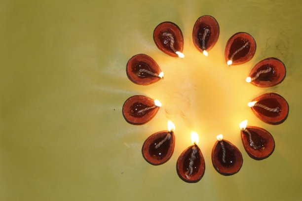 美丽的股票照片的传统橙色棕色赤陶土粘土diya灯燃烧在一个圆圈形成，黑暗和黄色的背景，文本复制空间。印度排灯节贺卡设计图片下载