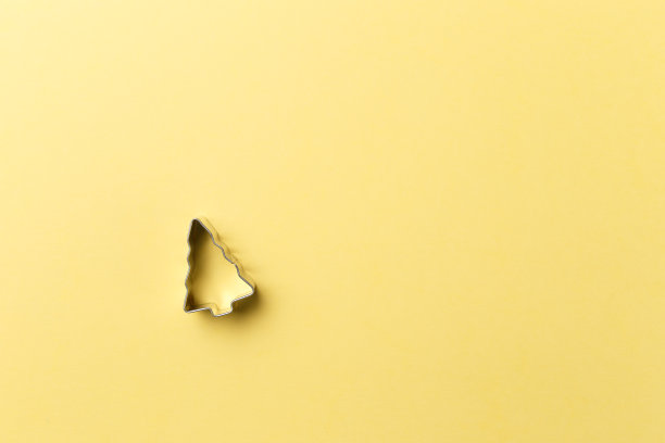 圣诞树曲奇切割机在黄色背景与复制空间。前视图。平的。时尚的彩色照片。以彩色纸为背景的简约风格。圣诞节的概念图片下载