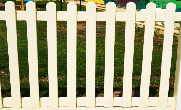 白色尖桩篱笆与绿色草地背景的特写图片下载