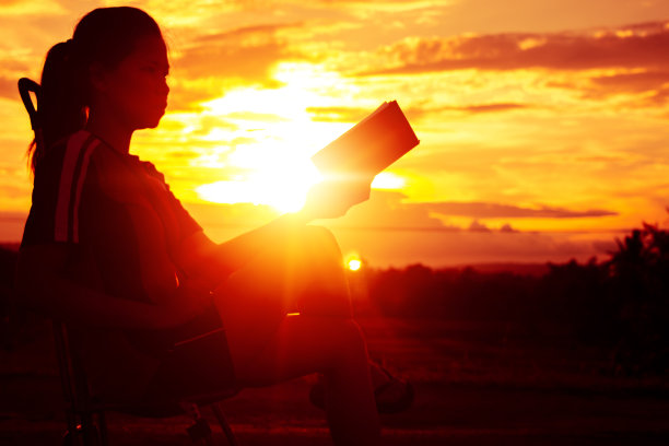 剪影女人坐着看一本书度假与美丽的自然。图片下载