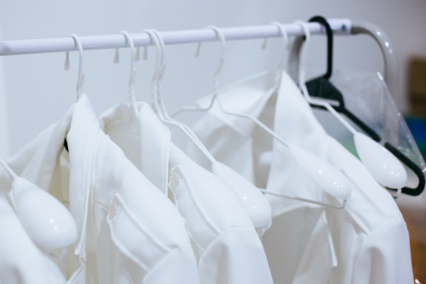 在医院的洗衣房，白色的医生服挂在衣架上。图片下载