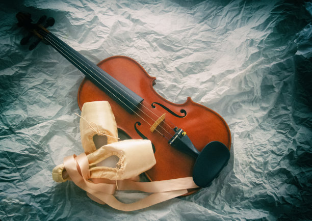 木制小提琴的抽象艺术设计背景放在粉色缎子芭蕾舞鞋旁边，在垃圾表面的底层图片下载