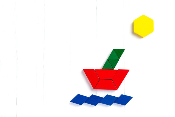 16、船在海浪上航行，阳光普照。夏天快乐的气氛。一个孩子玩着彩色积木，在一个浅色的木制背景上构建一个模型。图片下载