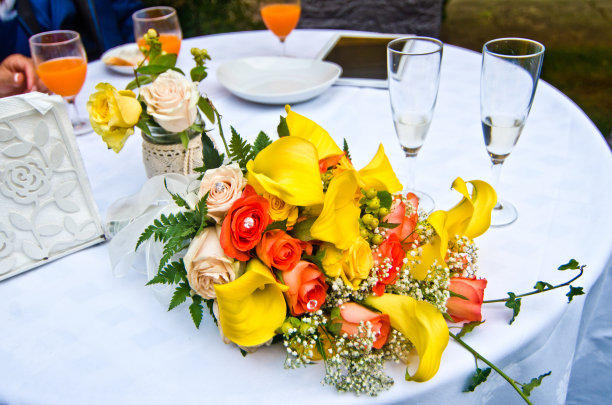 一束黄色、红色、橙色和粉色的花和两个酒杯准备给情侣图片下载