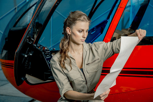 年轻的女直升机飞行员或机械师正在看地图。直升机坠毁图片下载