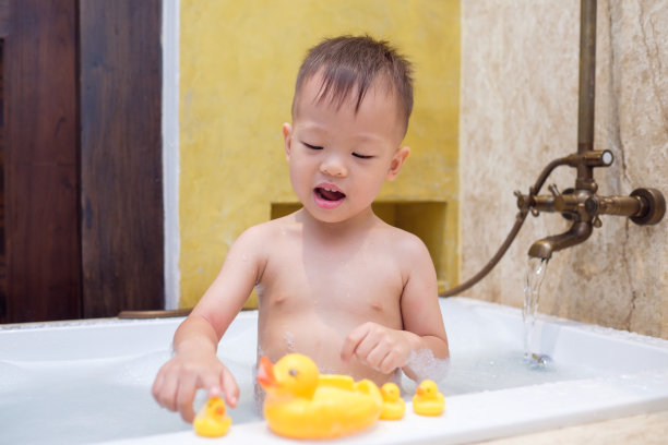可爱的亚洲小男孩，30个月/ 2岁的蹒跚学步的孩子，在浴缸里玩橡皮鸭玩具玩得很开心图片下载