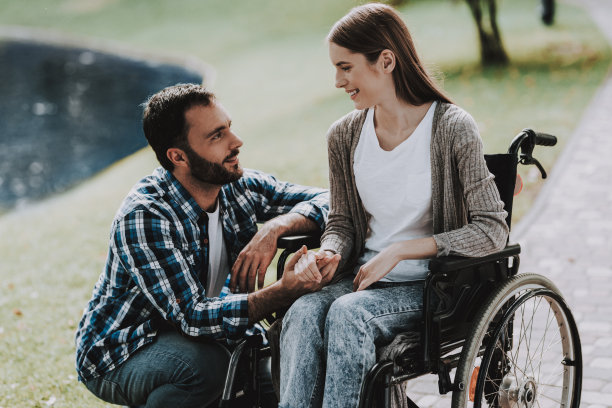 轮椅上的女孩和男友在夏日公园。图片下载