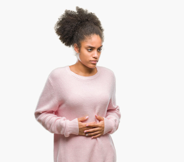 年轻的美国黑人妇女穿着冬季毛衣在孤立的背景与手在胃上，因为恶心，痛苦的疾病感觉不舒服。疼痛的概念。图片下载