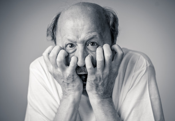 近距离的肖像，一个害怕害怕的老人在表达人类的情感和面部表情孤立在中性背景。图片下载