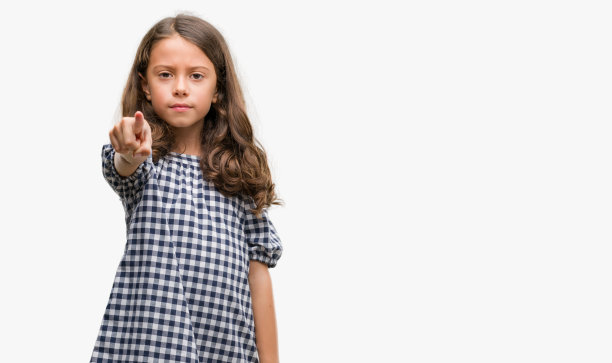 深色头发的西班牙裔女孩穿着黑白相间的裙子，手指指着相机和你，手势，正面自信的手势图片下载