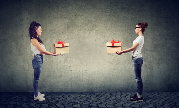 两个女人交换礼品盒，高兴地看着对方图片下载